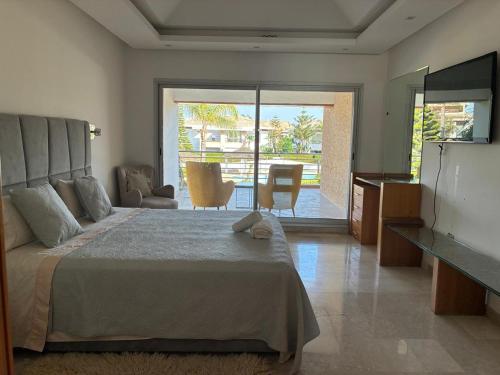 a bedroom with a bed and a television and a table at Villa 4 chambres Bouznika Bay by Saloua in Bouznika