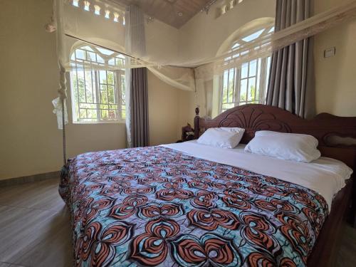 a bedroom with a large bed with a colorful bedspread at Akagera Sunset House in Kabarondo