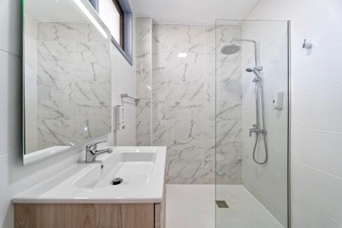a white bathroom with a sink and a shower at Fayna Apartments in Playa del Ingles