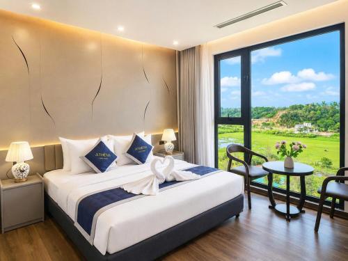 a bedroom with a bed and a table and a window at Athena Coto Hotel in Nam Cap