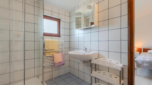 a white tiled bathroom with a sink and a mirror at Casa Aneri by Villas Guide in Pavicini