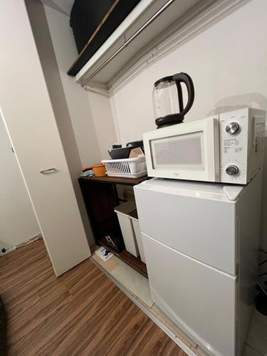 a microwave sitting on top of a white refrigerator at Rest one room大阪-阪急梅田駅から電車と徒歩で15分-神崎川駅から徒歩7分- in Osaka