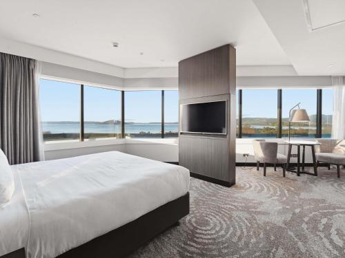 a bedroom with a large bed and a table with chairs at Pullman Rotorua in Rotorua