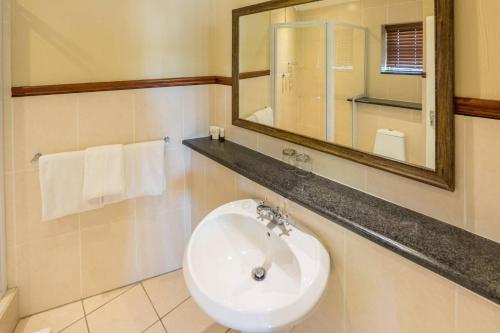 a bathroom with a sink and a mirror and towels at Constantia Hotel and Conference Centre in Midrand