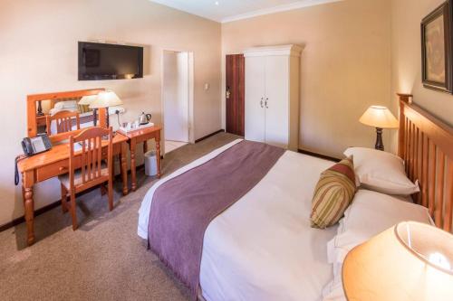 a bedroom with a bed and a desk and a sink at Constantia Hotel and Conference Centre in Midrand