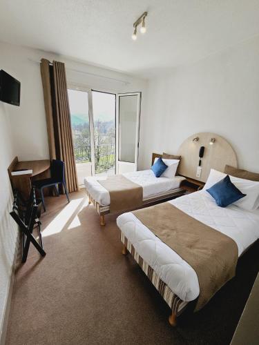 a hotel room with two beds and a desk at Adonis Lourdes - Notre Dame de la Sarte in Lourdes