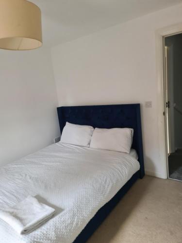 a bed with a blue headboard in a room at FV Dwelling in Nottingham