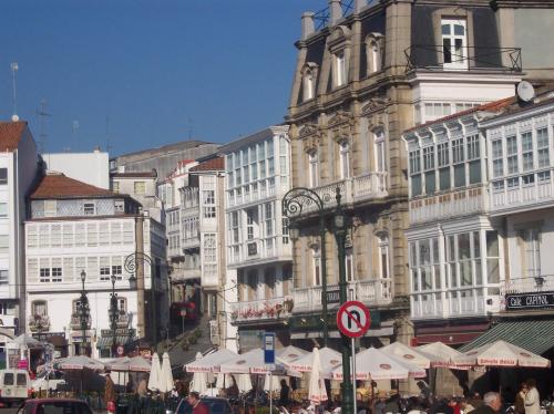 a busy city street with white umbrellas and buildings at Hotel Villa De Betanzos in Betanzos