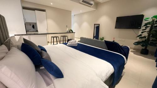 a bedroom with a large bed with blue and white pillows at Navy Studio By Bait Zain in As Sīfah