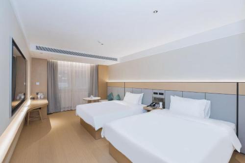 a hotel room with two beds and a television at JI Hotel Beijing Xizhimen in Beijing
