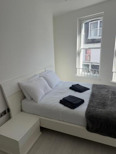 a white bed with two black towels on it at 1 bedroom flat in Saint Helier Jersey