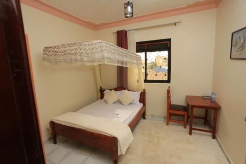 a bedroom with a bed and a table and a window at Grand View Hotel in Fort Portal