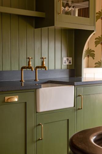 a kitchen with green cabinets and a sink at Castle Lodge in Ludlow