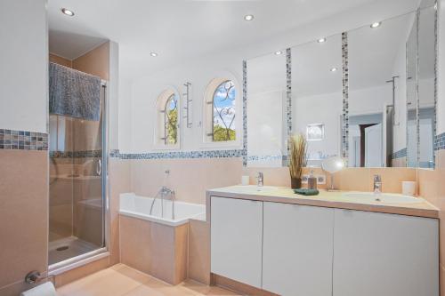 a bathroom with two sinks and a shower and a tub at Villa Etoile in Cabasse