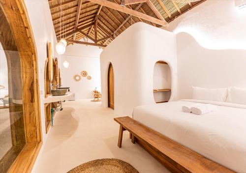 a bedroom with a white bed and a wooden bench at Lombok Souls in Senggigi