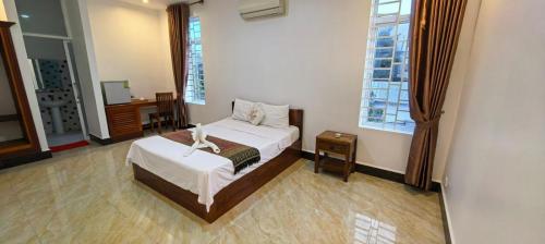 a bedroom with a bed and two windows at Khmer House Kampot Boutique in Kampot