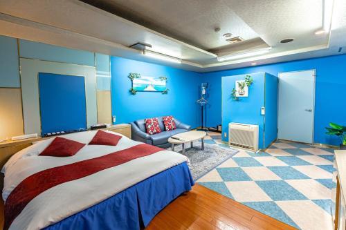 a bedroom with blue walls and a bed and a couch at Earn Exception in Isesaki