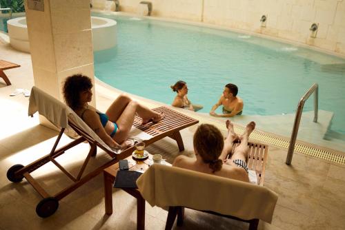 a group of people sitting in chairs in a swimming pool at Mona Plaza Zlatibor in Zlatibor
