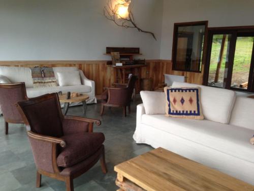 a living room with couches and chairs and a table at Mallin Colorado Ecolodge in Aldana