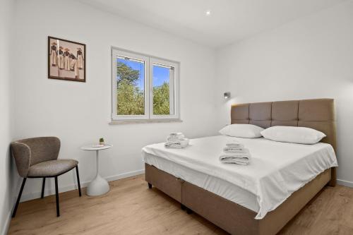 a white bedroom with a bed and a chair at Danijela Holiday Home in Labin