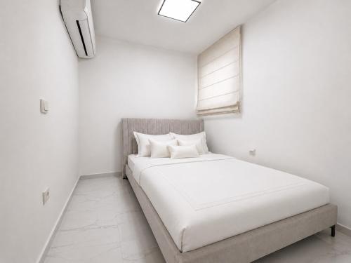 a white bedroom with a bed and a window at ODAR suite in Caesarea