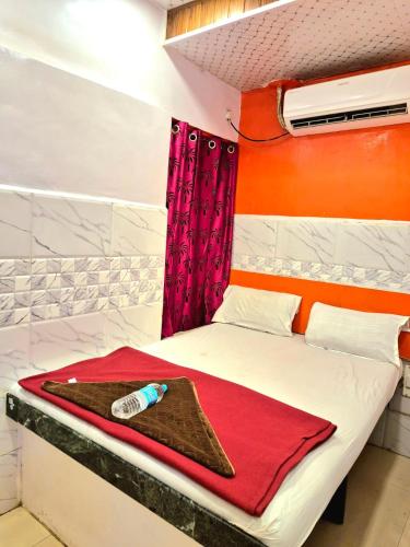 a bedroom with a bed with a red curtain and a bottle on it at Hotel firdous in Mumbai