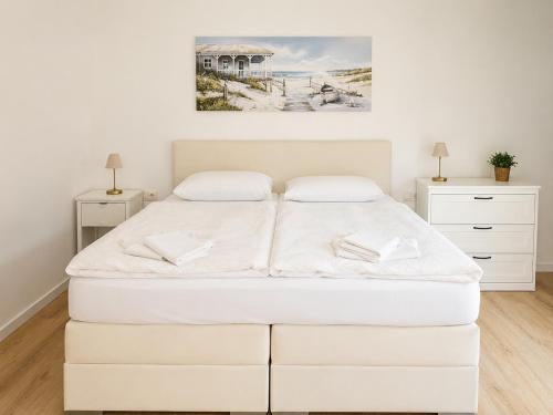 a white bedroom with a bed and a painting on the wall at Zimmer-Vermietung an der Ostsee, neben der Median-Klinik in Wismar