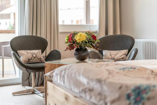 a room with chairs and a table with a vase of flowers at Naudererhof - 4-Stern-Superior in Nauders