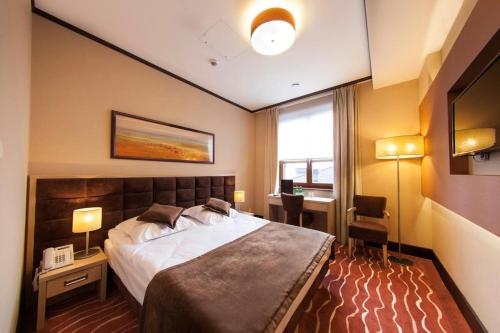 a bedroom with a bed and a desk and a window at Hotel Skarbek in Lubin