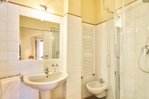 a white bathroom with a sink and a shower at Casa Becci Central Large & Sunlit Historical Flat in San Gimignano