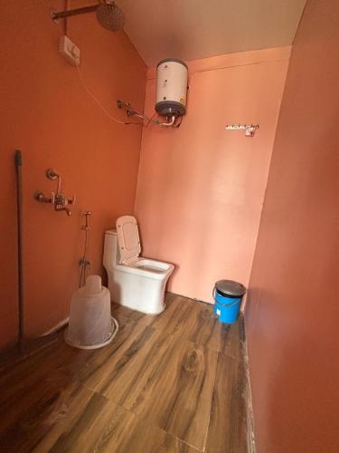 a bathroom with a toilet and a trash can at Om Guesthouse in Rishīkesh