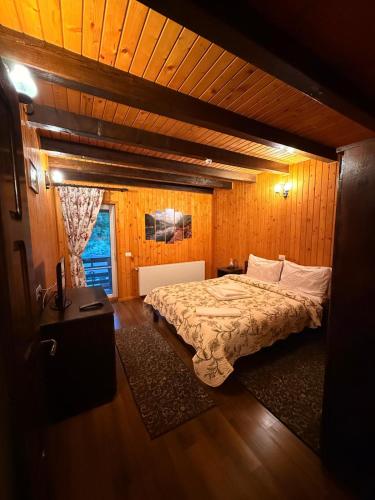 a bedroom with a bed in a wooden room at Pensiunea Ana in Ceahlău