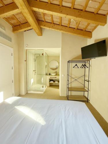 a bedroom with a white bed and a television at Boutique Hotel Atelier - Adults only in Sant Pere Pescador
