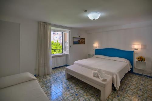a bedroom with a bed and a couch and a window at Amalfi Hotel centro storico in Amalfi