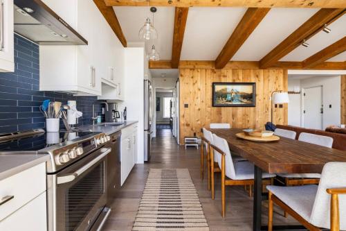 a kitchen with white cabinets and a wooden table at Mountainside Top Floor Condo - Treetops Lionshead in Vail