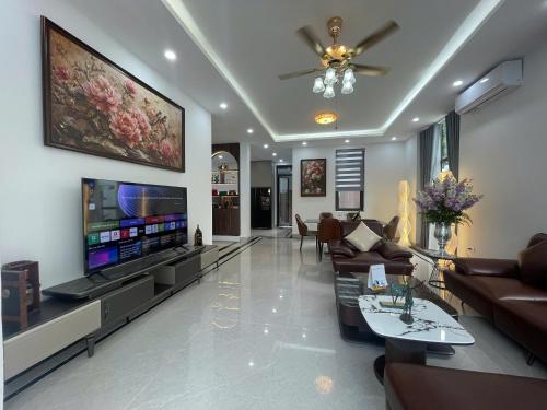 a living room with couches and a large tv at Van Khe Cozy Villa in Hà Ðông