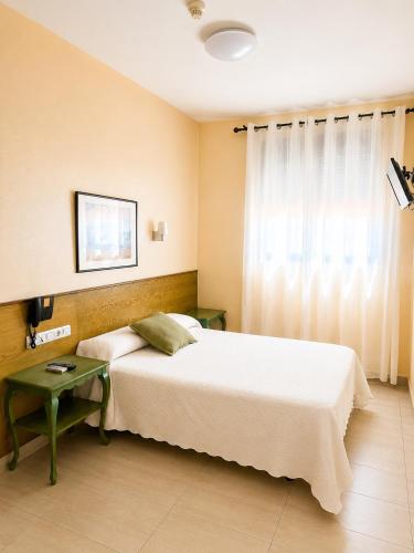 a bedroom with a bed and a table and a window at Hostal la Abuela in Simancas