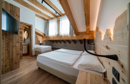 a bedroom with a bed and a bathroom with a window at Residence Lastei in San Martino di Castrozza