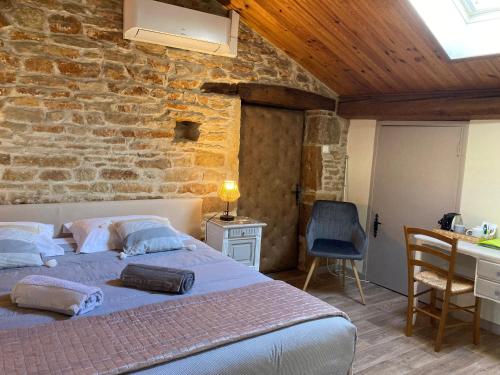 a bedroom with a bed and a stone wall at LA PASSIFLORE in Azé