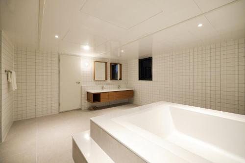 a white bathroom with a tub and a sink at Anook Hotel Suwon Ingye in Suwon