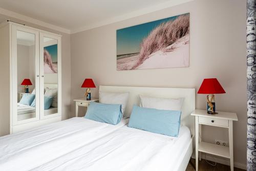 a bedroom with a white bed with blue pillows at Hotel & Ferienunterkünfte Hus Seeblick in Fehmarn