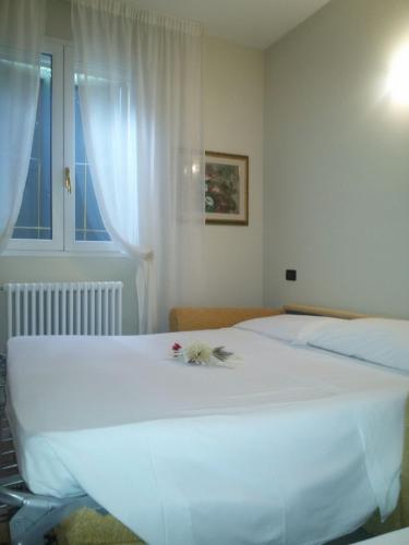 a bedroom with a white bed with flowers on it at Hotel Bruna in Lizzano in Belvedere