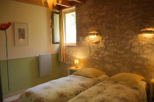 a bedroom with a bed and a stone wall at Domaine du Roujos - Gite Ocre in Beaumont-de-Lomagne
