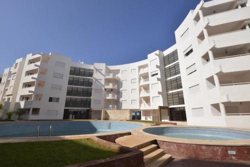 an apartment complex with a swimming pool in front of a building at Escale BOUZNIKA Centre in Bouznika