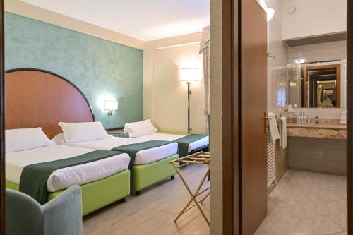 a hotel room with two beds and a bathroom at Hotel Principe in Pomezia