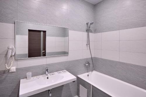 a bathroom with a sink and a tub and a mirror at Art-Hotel in Khosta