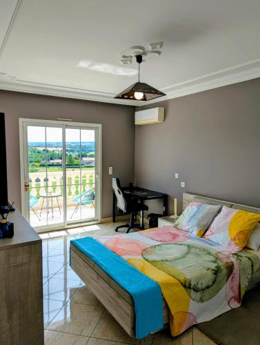 a bedroom with a bed and a desk and a balcony at Jardhelena in Jardin