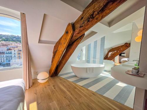a bathroom with a large window and a bath tub at Hôtel L'orque Bleue in Sète