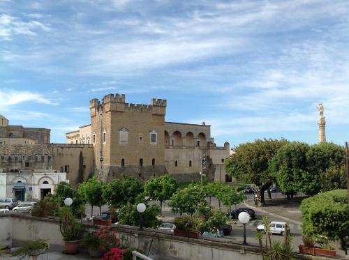 un gran edificio de ladrillo con una torre en el fondo en Hotel Castello, en Mesagne