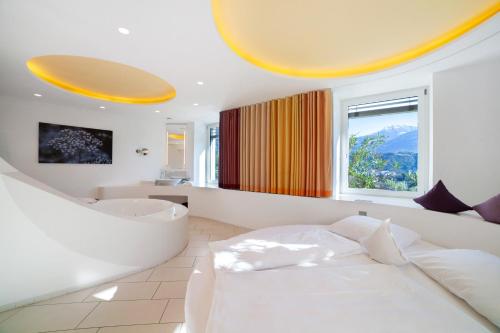 a bedroom with a bed and a tub and a sink at Bio Wellnesshotel Pazeider in Marlengo